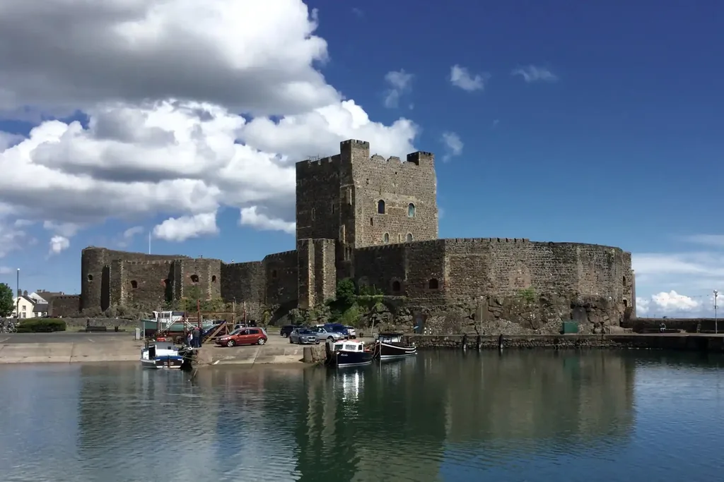 Carrickfergus Castle seen across the harbour in County Antrim, with fishing boats moored below the walls