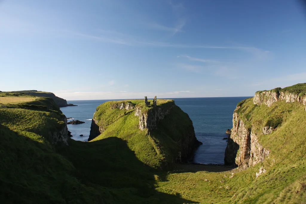 The ruined tower of Dunseverick Castle standing on its grassy basalt headland above the sea on the Causeway Coast